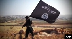 "Ислам мемлекеті" (ИМ) экстремистік ұйымының YouTube желісіне жариялаған видеосынан алынған скриншот. (ИМ мүшесі ұйымның туын көтеріп тұр)