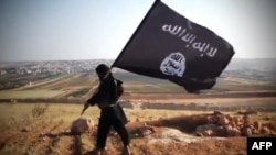 Член группировки, связанной с "Исламским государством", несет черное знамя ИГ.