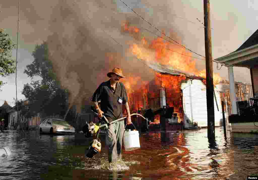 A man walks through floodwater as a home burns during the aftermath of Hurricane Katrina in New Orleans on September 6.