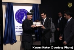 Kawun Kakar (R) presents a selection of his father Hassan Kakar's books to the Afghanistan President Ashraf Ghani on January 5.