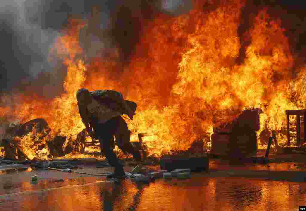 An activist runs from a burning barricade on Khreshchatyk Street near Independence Square, also known as the Maidan.