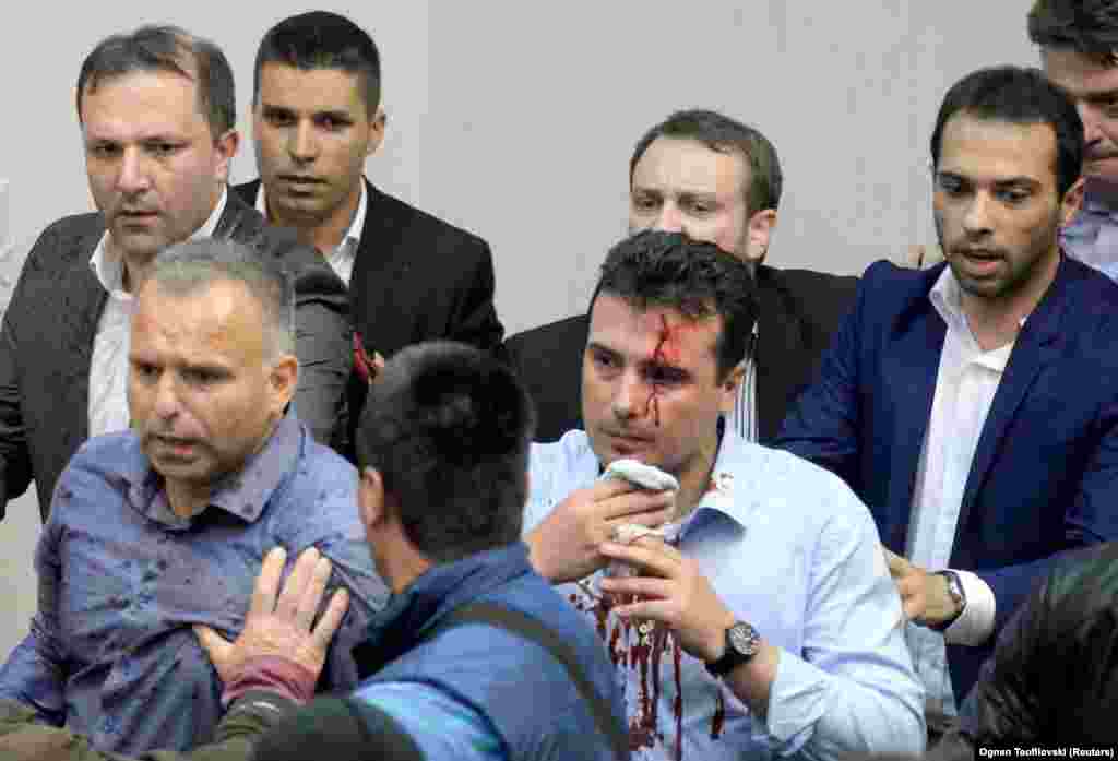 Zoran Zaev, the head of a newly formed coalition in Macedonia that said it was trying to assert its right to govern by electing the new parliament speaker, is escorted from parliament on April 27 with blood streaming from his head after protesters stormed the building and assaulted him. (Reuters)&nbsp;