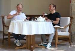 Russian President Vladimir Putin and then-Prime Minister Dmitry Medvedev drink tea during breakfast at the state residence in Sochi in 2015.