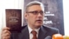 Former Prime Minister Mikhail Kasyanov holds up a copy of the report "Putin. Corruption," at its presentation on March 28.