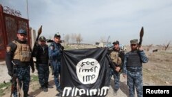 Іракські силовики тримають догори дригом на знак зневаги прапор угруповання «Ісламська держава», який вони здерли у визволеній частині Мосула, 27 лютого 2017 року