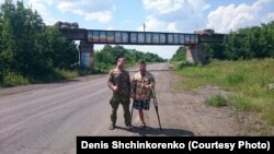 Денис Шинкоренко (ліворуч) та Андрій Камаєв стоять біля мосту, обмальованого словом «Новоросія». Схід України, вересень 2015 року 