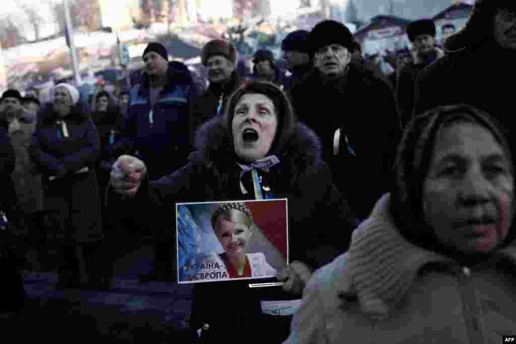 An elderly Ukrainian woman holding a piccture of jailed opposition leader Yulia Tymoshenko shouts slogans while watching a parliament session on a video wall on Kyiv&#39;s Independence Square. (AFP/Angelos Tzortzinis)