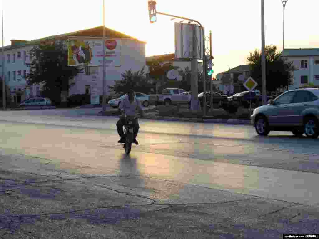 Gün ýaşyp barýan mahaly Aşgabadyň köçeleriniň birinden geçip barýan motosiklli adam.