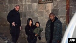 Armenia -- US reality TV star Kim Kardashian holds her daughter (C) in her arms next to her rapper husband Kanye West (R) as they walk close to the Geghard Monastery, April 9, 2015