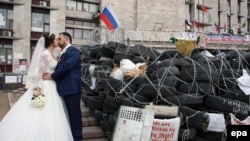 Новобрачные целуются у баррикады в центре города Донецка. 2 мая 2014 года.