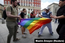 Гейлерге қарсылар Мәскеудің орталығында акцияға шыққан ЛГБТ өкілдерінің туын тартып алуға әрекет жасап жатыр. 2015 жыл.