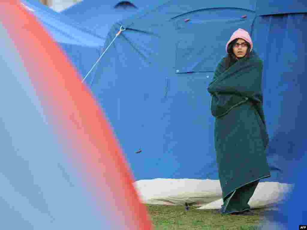 Italy - A woman stands outside a tent after spending the night in a stadium in the Abruzzo capital of L'Aqula, 07Apr2009 - Par2496044 Object name ITALY - QUAKE ITALY, L'Aquila : A woman stands outside a tent on April 7, 2009 after spending the night in a stadium in the Abruzzo capital of L'Aquila, the epicenter of an earthquake that struck on April 6. The death toll from the powerful quake that rocked central Italy has risen to 179, with 34 people reported missing, rescue workers in the town of L'Aquila said on April 7. AFP PHOTO / / MARIO LAPORTA 