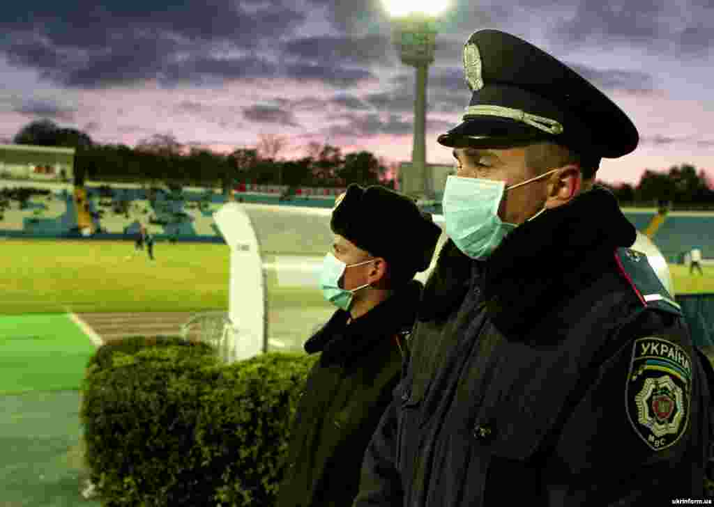 Police officers wear protective masks during a Ukrainian Premier League match.