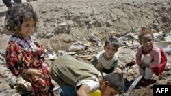 Iraq -- An Iraqi boy drinks from a broken waterpipe on the edge of a waste water reservoir northeast of Baghdad, 21May2006