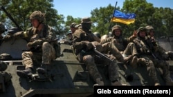 Українські військовослужбовці їдуть на бронетранспортері по дорозі на Донеччині, 7 липня 2022 року