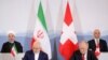 Swiss President Alain Berset and Iranian President Hassan Rohani look on as Johann Schneider-Ammann, Head of the Federal Department of Economic Affairs, Education and research and Iran's Foreign Minister Mohammad Javad Zarif sign documents 