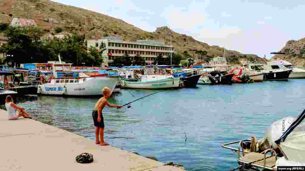 Хлопчик ловить рибу на набережній Балаклави