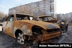 Остовы машин, сгоревших в результате обстрела Мариуполя "Градами" месяц назад, по-прежнему стоят во дворах