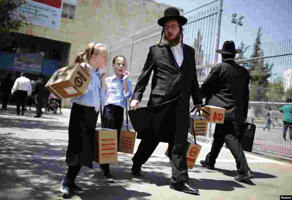 An ultra-Orthodox Jewish man walks out with his children after collecting gas-mask kits at a distribution point in Jerusalem. Thousands of Israelis continue to queue up for gas masks or ordered them by phone, spurred on by fears that any Western military response to last week's alleged chemical-weapons attack in Syria could ensnare their own country in war. (Reuters/Amir Cohen)