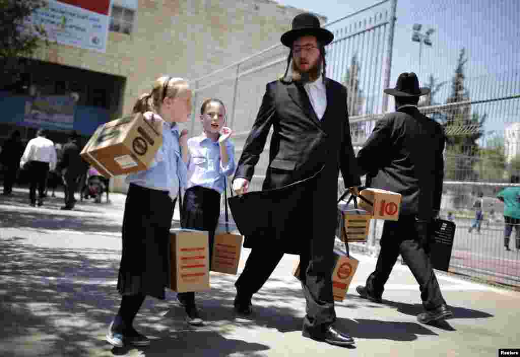 An ultra-Orthodox Jewish man walks out with his children after collecting gas-mask kits at a distribution point in Jerusalem. Thousands of Israelis continue to queue up for gas masks or ordered them by phone, spurred on by fears that any Western military response to last week&#39;s alleged chemical-weapons attack in Syria could ensnare their own country in war. (Reuters/Amir Cohen)