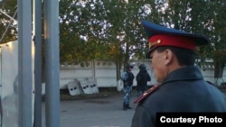 Павлодар түрмесінің алдында тұрған полиция қызметкері және арнайы жасақ өкілдері.