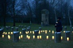 Cehia: un copil aprindde o lumânare la cimitirul evreiesc de la fostul lagăr nazist de concentrare de la Terezin, 27 ianuarie 2020.