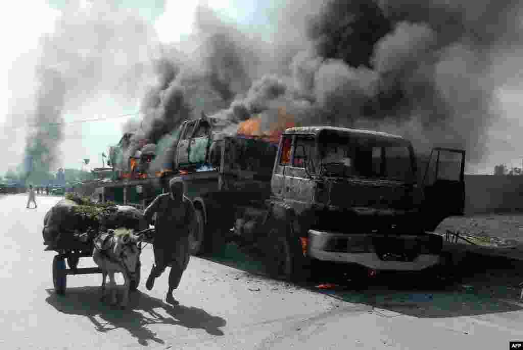 A man leads his donkey-cart past a burning trailer truck transporting NATO vehicles following an attack by gunmen in the Wazir Dhand area of Khyber province, Pakistan, on May 5. (AFP)