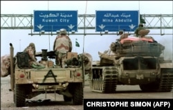 Американський джип Hummvee (l) і саудівський танк проїжджають під дорожнім знаком, що спрямовує їх до міста Кувейт, 26 лютого 1991 року під час наступу сил союзників 