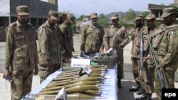 Pakistani Army soldiers show arms and ammunition recovered during operations against Taliban militants in Charbagh.