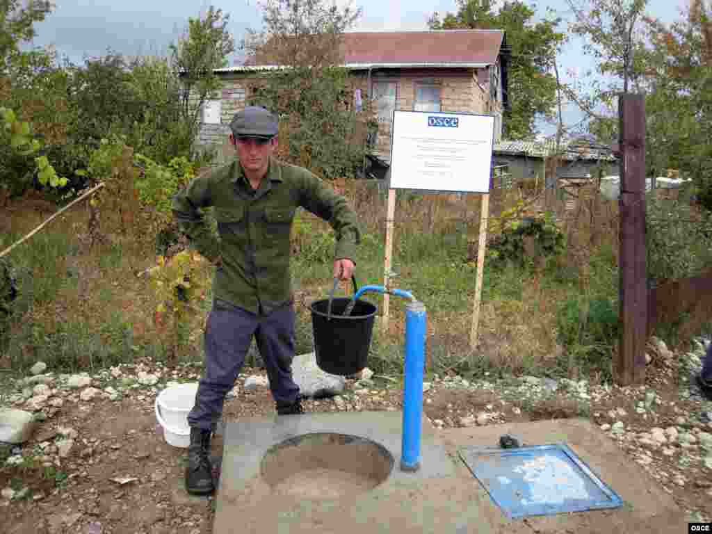 A villager in Georgia collects water from a source provided by an OSCE development project.