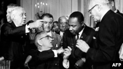Президент США Линдон Джонсон пожимает руку Мартину Лютеру Кингу после подписания "Закона о гражданских правах" в стенах Белого дома. Вашингтон, 2 июля 1964 года.