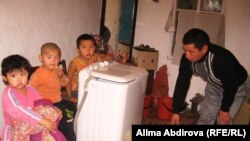 Кожагельды Абдиров, отец-одиночка, занимается стиркой, рядом сидят его дети. Актобе, 20 ноября 2010 года.