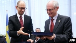 European Council President Herman Van Rompuy (right) exchanges documents with Ukrainian Prime Minister Arseniy Yatsenyuk during the signing of the political provisions of the bloc's Association Agreement with Ukraine in Brussels on March 21.