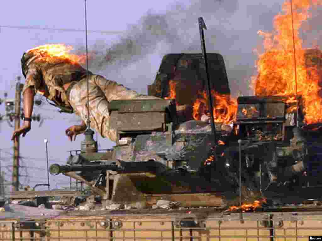 British soldier jumps from a burning tank which was set ablaze after a shooting incident in the southern Iraqi city of Basra September 19, 2005. Angry crowds attacked a British tank with petrol bombs and rocks in Basra on Monday after Iraqi authorities said they had detained two British undercover soldiers in the southern city for firing on police. Two Iraqis were killed in the violence, an Interior Ministry official said. REUTERS/Atef Hassan 