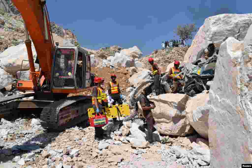 Rescue workers stand beside the wreckage of a damaged truck after the fatal incident in the marble quarry.