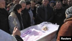 People pay their respects at the coffin of Oksana Makar during her funeral outside the town of Mykolayiv on March 31.
