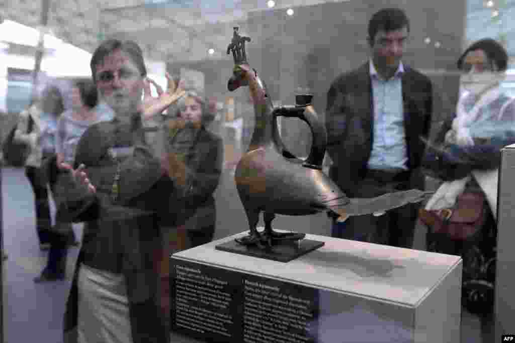 Visitors examine a vase titled "Paon-Aquamanile" from Spain.