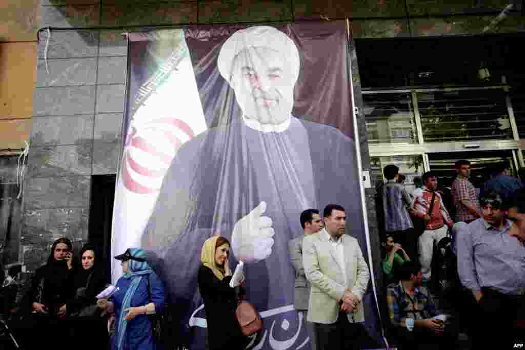 People gather under a portrait of Rohani outside his campaign headquarters after the announcement of his victory on June 15.