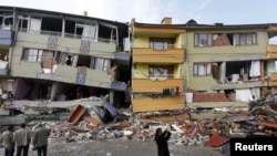 Turkey -- Earthquake survivors stand in front of a damaged building in Ercis, 26Oct2011