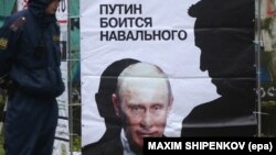 Russia -- A police officer stands near a placard depicting opposition leader and anti-corruption blogger Aleksei Navalny's shade (R) benting over President Vladimir Putin in Kirov, October 16, 2013