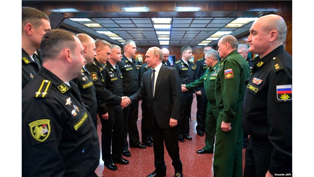Vladimir Putin shakes hands with officers while visiting the a missile cruiser in the Black Sea.