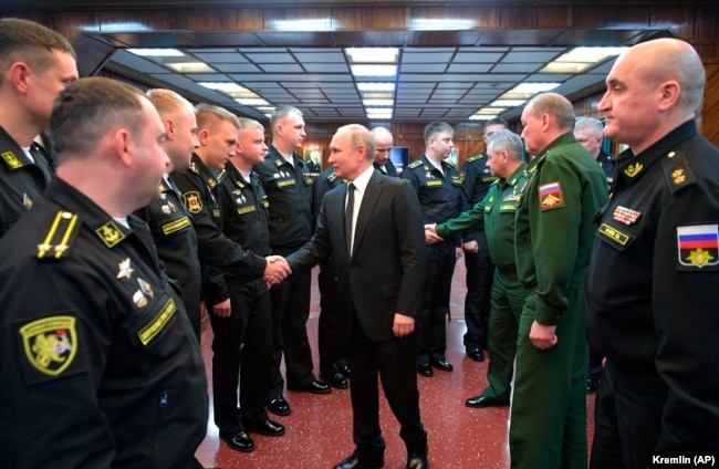 Vladimir Putin shakes hands with officers while visiting the a missile cruiser in the Black Sea.
