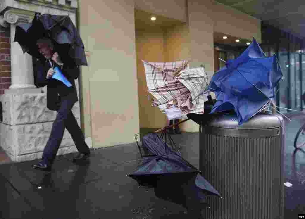 A man passes by discarded umbrellas during heavy rain in New South Wales, Australia. More than 20 people have been rescued from floodwaters and 215,000 homes and businesses are without power as storms lashed New South Wales. (epa/David Moir)