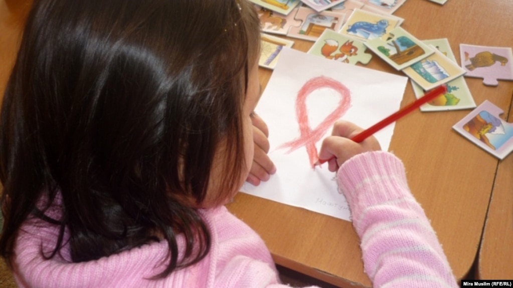 An HIV-infected child draws a Red Ribbon, the international symbol of HIV and AIDS awareness, at the Center for Maternity and Childhood in Shymkent in this 2010 photo.