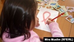 An HIV-infected child draws a Red Ribbon, the international symbol of HIV and AIDS awareness, at the Center for Maternity and Childhood in Shymkent in this 2010 photo.