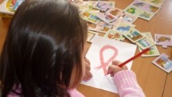 Девочка рисует красную ленточку — символ борьбы со СПИДом — в центре материнства и детства в Шымкенте. 30 ноября 2010 года.