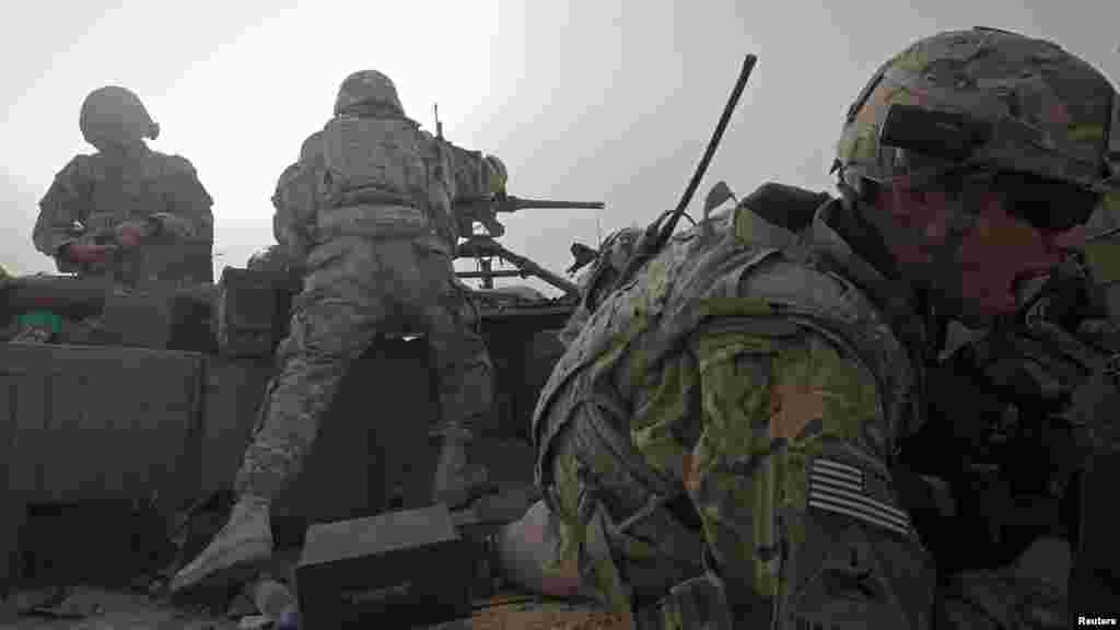 A U.S. soldier speaks on a radio as others fire on a Taliban position in Logar Province, Afghanistan, on May 25. (Reuters/Danish Siddiqui)