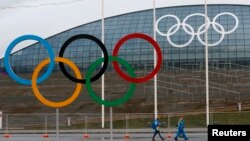 Volonteri prolaze pored olimpijskih krugova ispred ledene dvorane u Olimpijskom parku u Sočiju