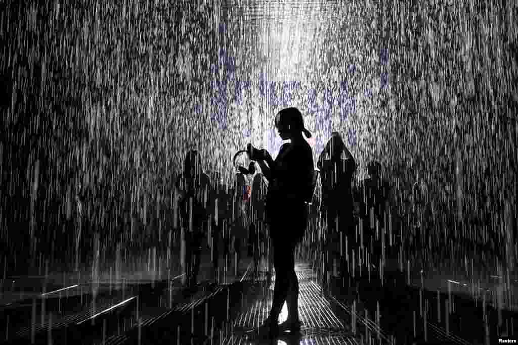 People visit the Rain Room, an installation by Random International, at a museum in Shanghai. The installation creates a field of falling water that stops in the area where people are walking through, allowing them to remain dry. (Reuters/Aly Song)