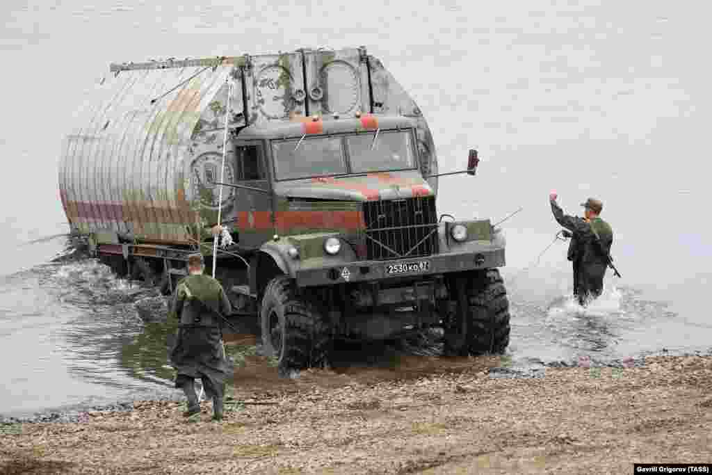 A section of a pontoon bridge being backed into the Tom River. 